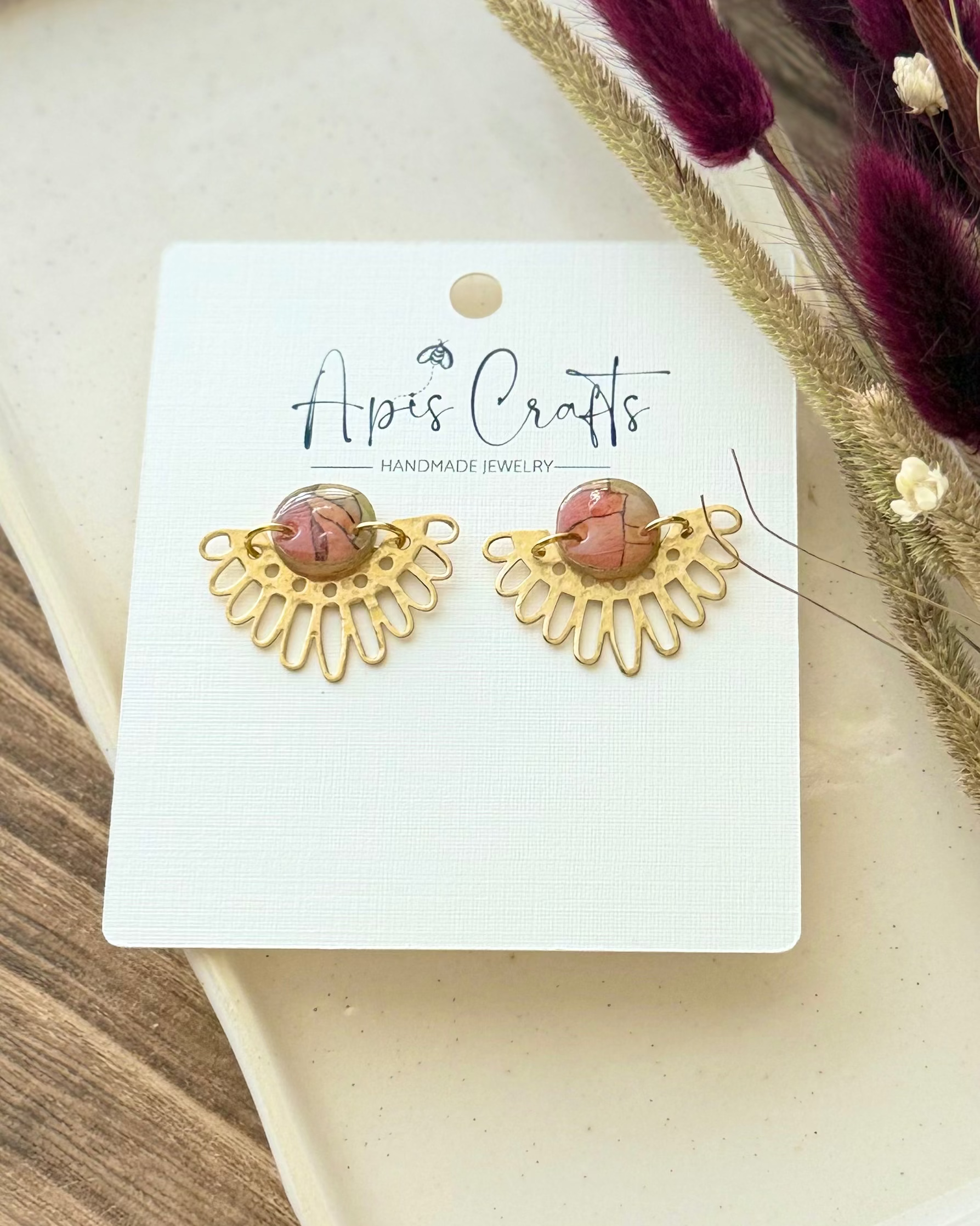 A pair of handmade gold sunburst-shaped earrings with stained glass cabochon stones