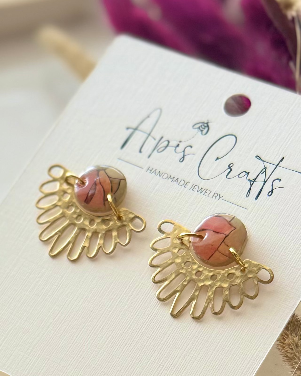 A pair of handmade gold sunburst-shaped earrings with stained glass cabochon stones