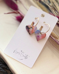 Heart-shaped dangling earrings with a colorful marbled pattern in pink, purple, and blue
