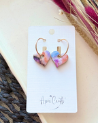 Heart-shaped dangling earrings with a colorful marbled pattern in pink, purple, and blue