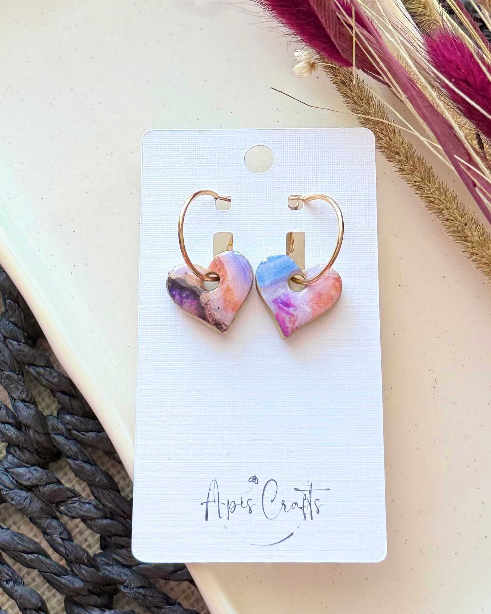 Heart-shaped dangling earrings with a colorful marbled pattern in pink, purple, and blue