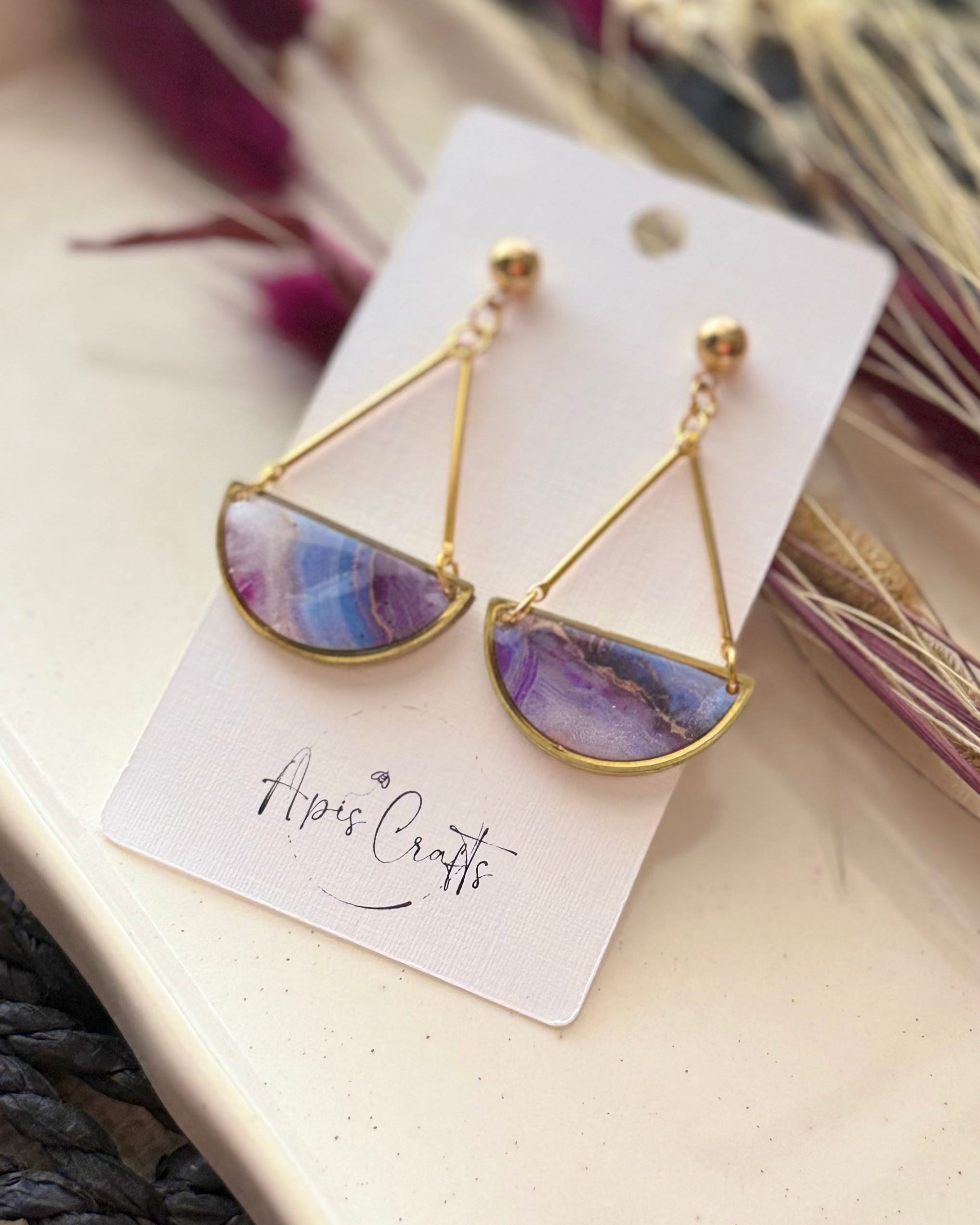 Gold-tone dangle earrings with semicircle marble stone pendants in purple, blue, and pink,