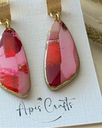 A pair of dangle earrings with textured gold caps and wedge-shaped pink and red faux stone drops