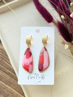 A pair of dangle earrings with textured gold caps and wedge-shaped pink and red faux stone drops