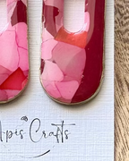 A pair of statement earrings with rectangular ppendants filled with layered pink and red faux stone design, attached to gold square studs