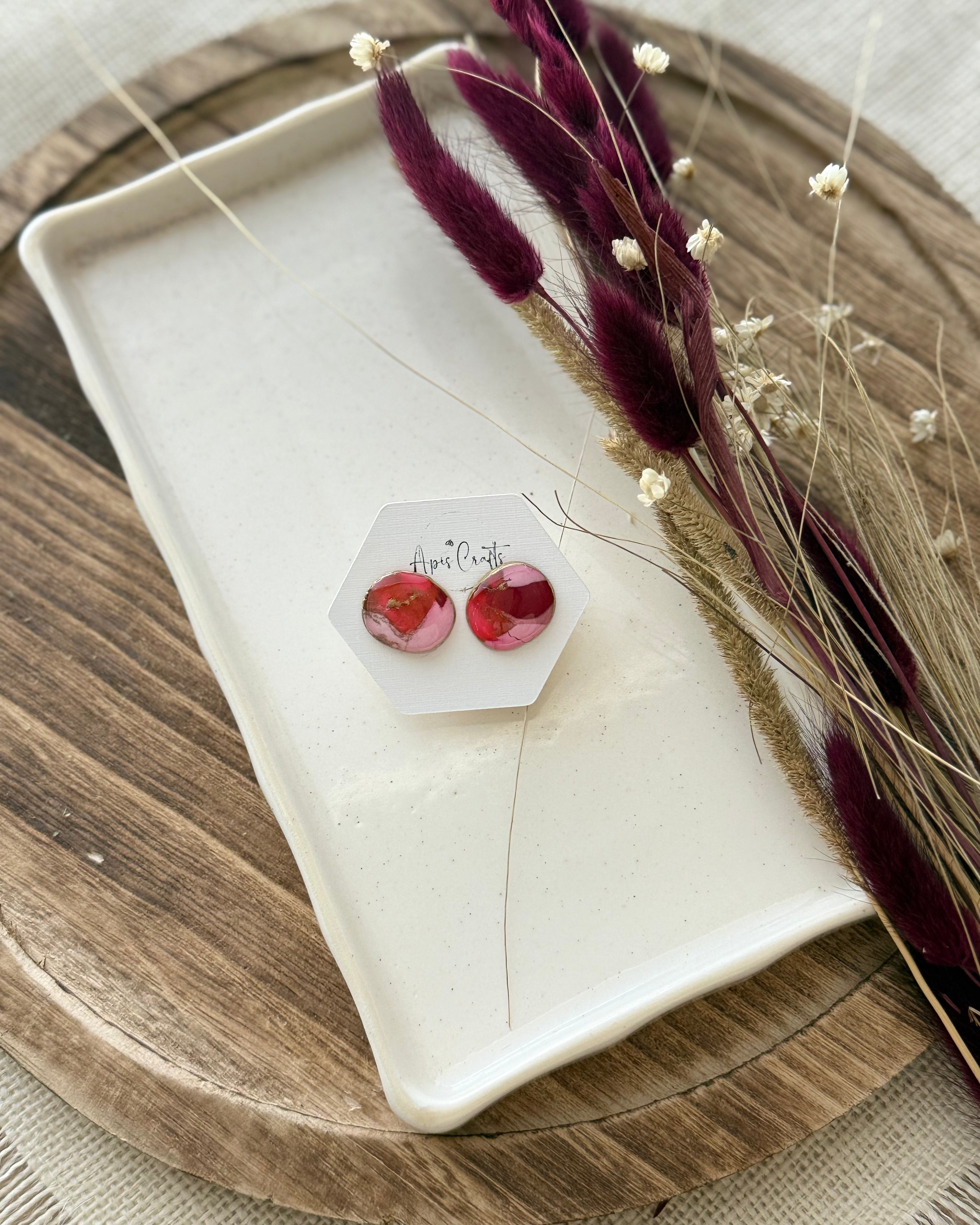 A pair of pebble shaped stud earrings with oval pink and red faux stone finish