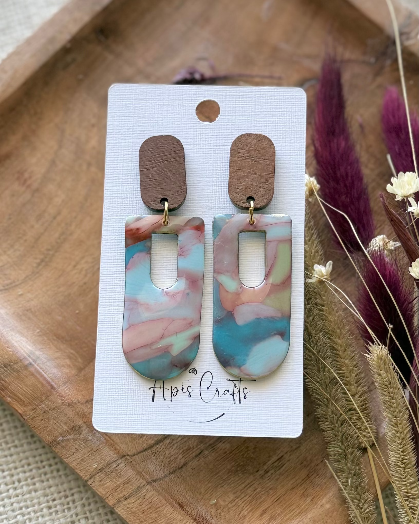 A pair of dangling with rectangular marbled drops in pink, blue, and white, with brown wooden top pieces.