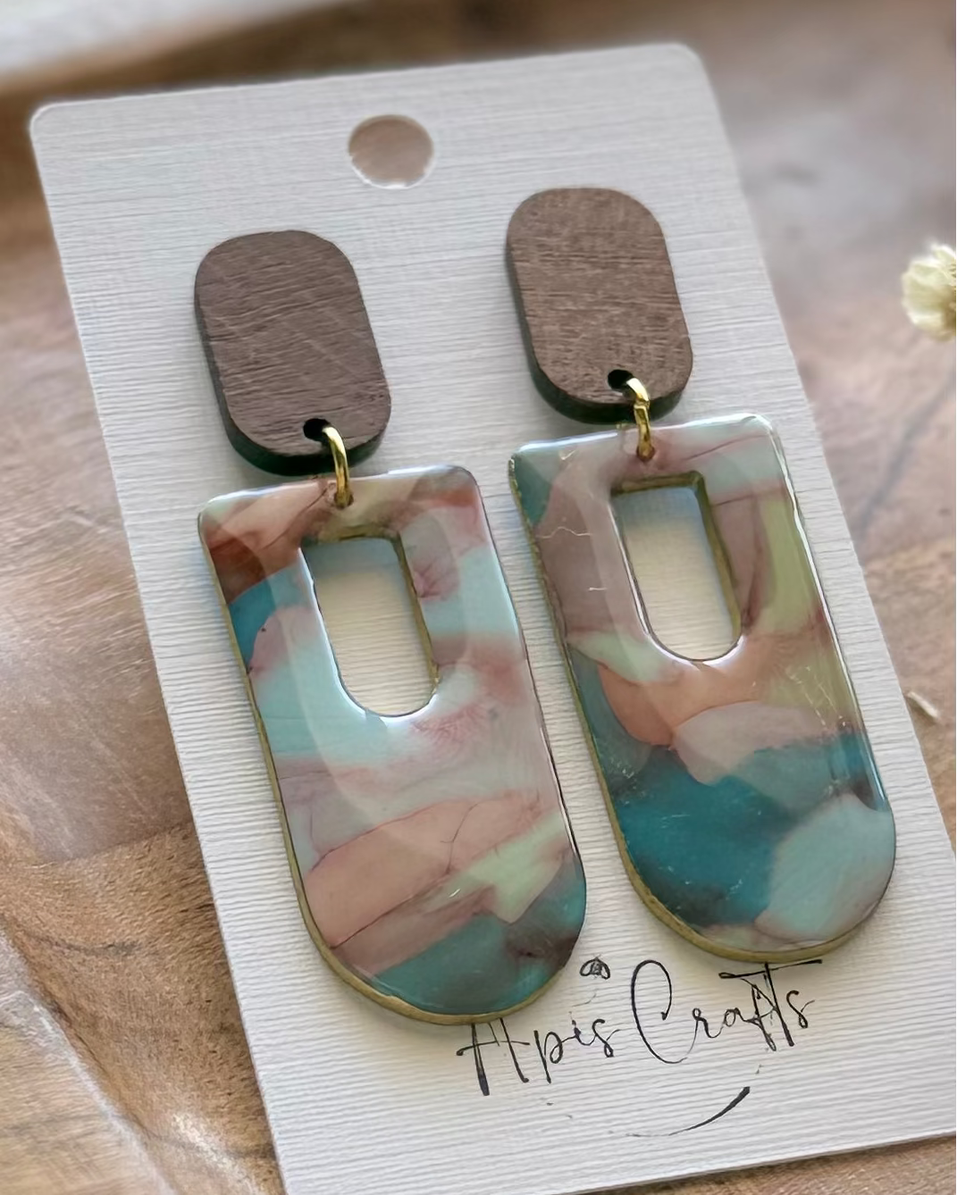 A pair of dangling with rectangular marbled drops in pink, blue, and white, with brown wooden top pieces.