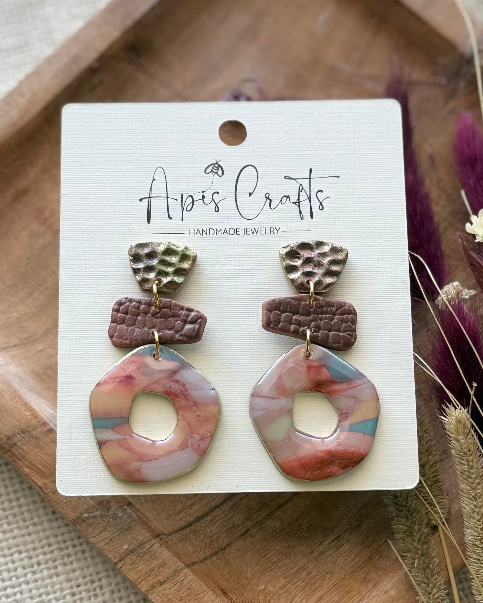 A pair of handmade geometric drop earrings featuring textured donut medallions