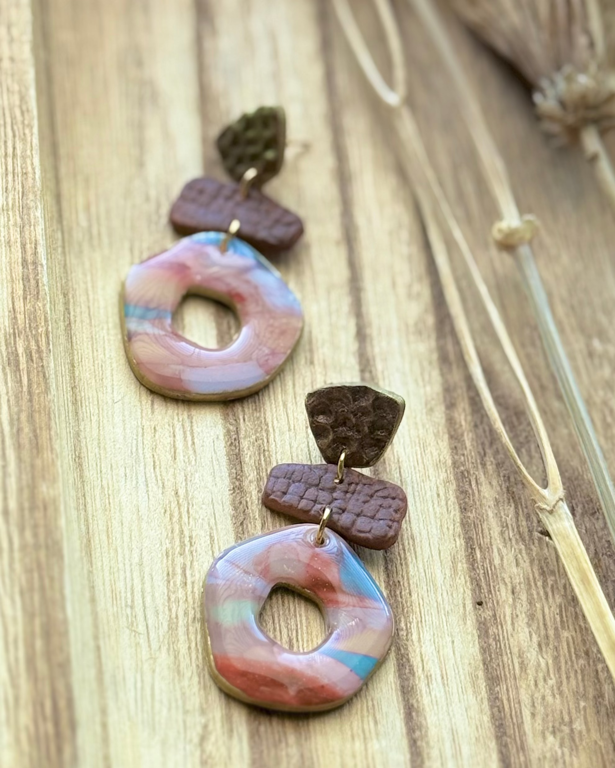 A pair of handmade geometric drop earrings featuring textured donut medallions