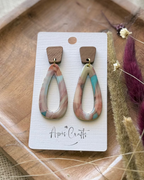A pair of teardrop-shaped drop earrings with a marbled pattern of pink, beige, and turquoise