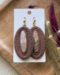 A pair of oval drop earrings with textured dark brown outer rings and marbled pastel inlay center
