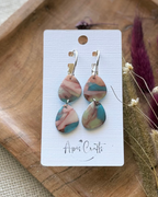 A pair of teardrop-shaped drop earrings with marbled pink, blue, and green resin-like patterns