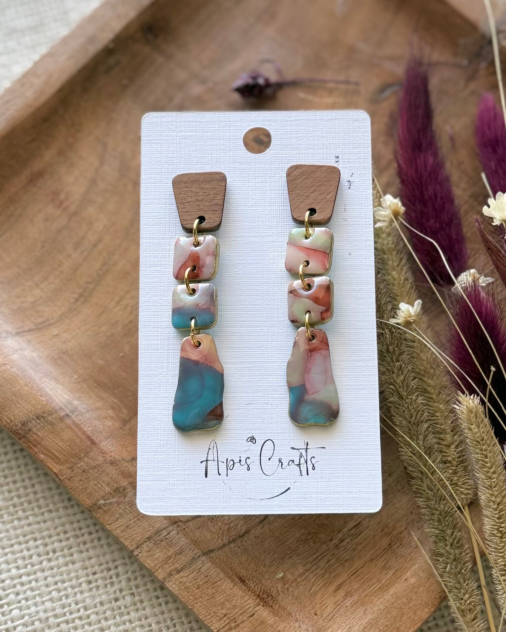A pair of handmade dangle earrings with textured drops and a dangling marbled bottom piece in blue, pink, and cream.