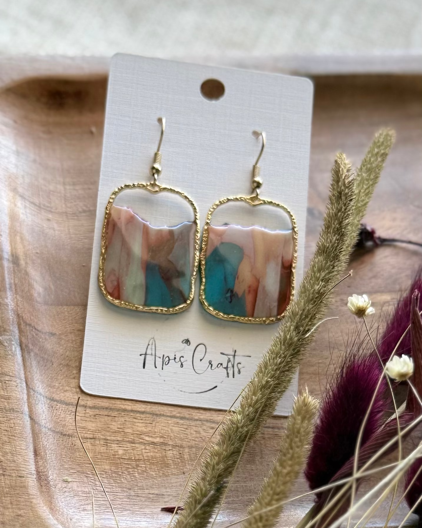 A pair of gold-tone drop earrings with rectangular marbled pendants in soft pastel tones