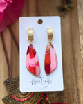 A pair of dangle earrings with textured gold caps and wedge-shaped pink and red faux stone drops