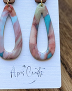 A pair of teardrop-shaped drop earrings with a marbled pattern of pink, beige, and turquoise