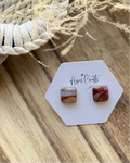 A pair of small square stud earrings with layered red, white, and brown marbled texture