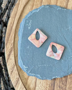 Diamond shaped charm with a teardrop keyhole in a pink and sand limestone