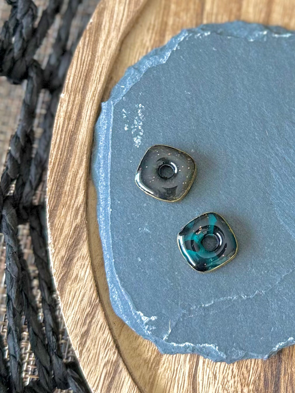 Two small teardrop-shaped stone beads with holes, one black and one jade