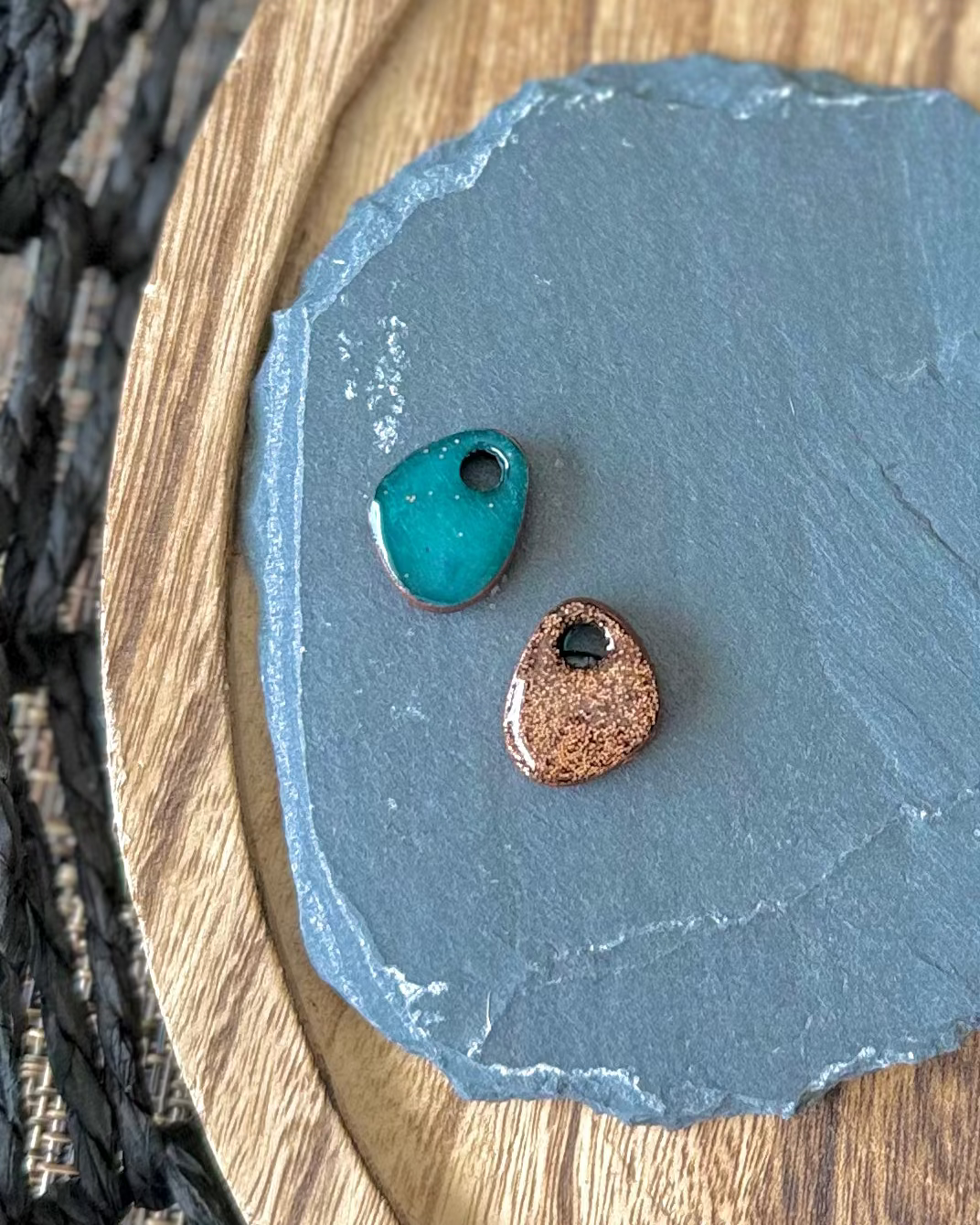 Two small teardrop-shaped stone beads with holes, one turquoise blue and one rose gold